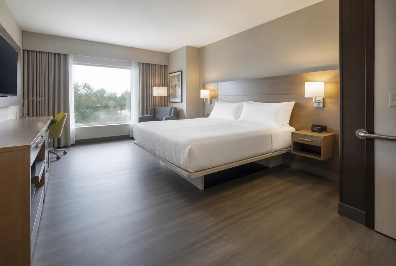 Accessible hotel guest room with an open bed base and generous clear floor space alongside