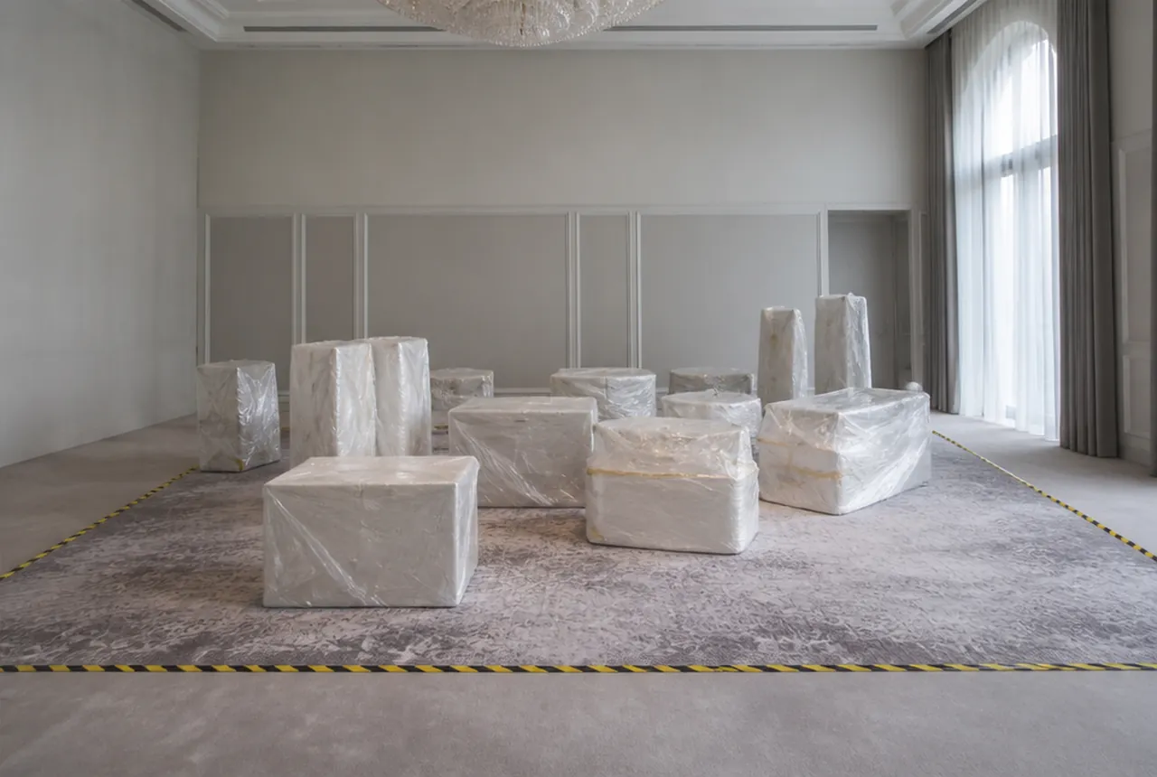 Wrapped furniture pieces grouped inside an empty room behind a floor marking